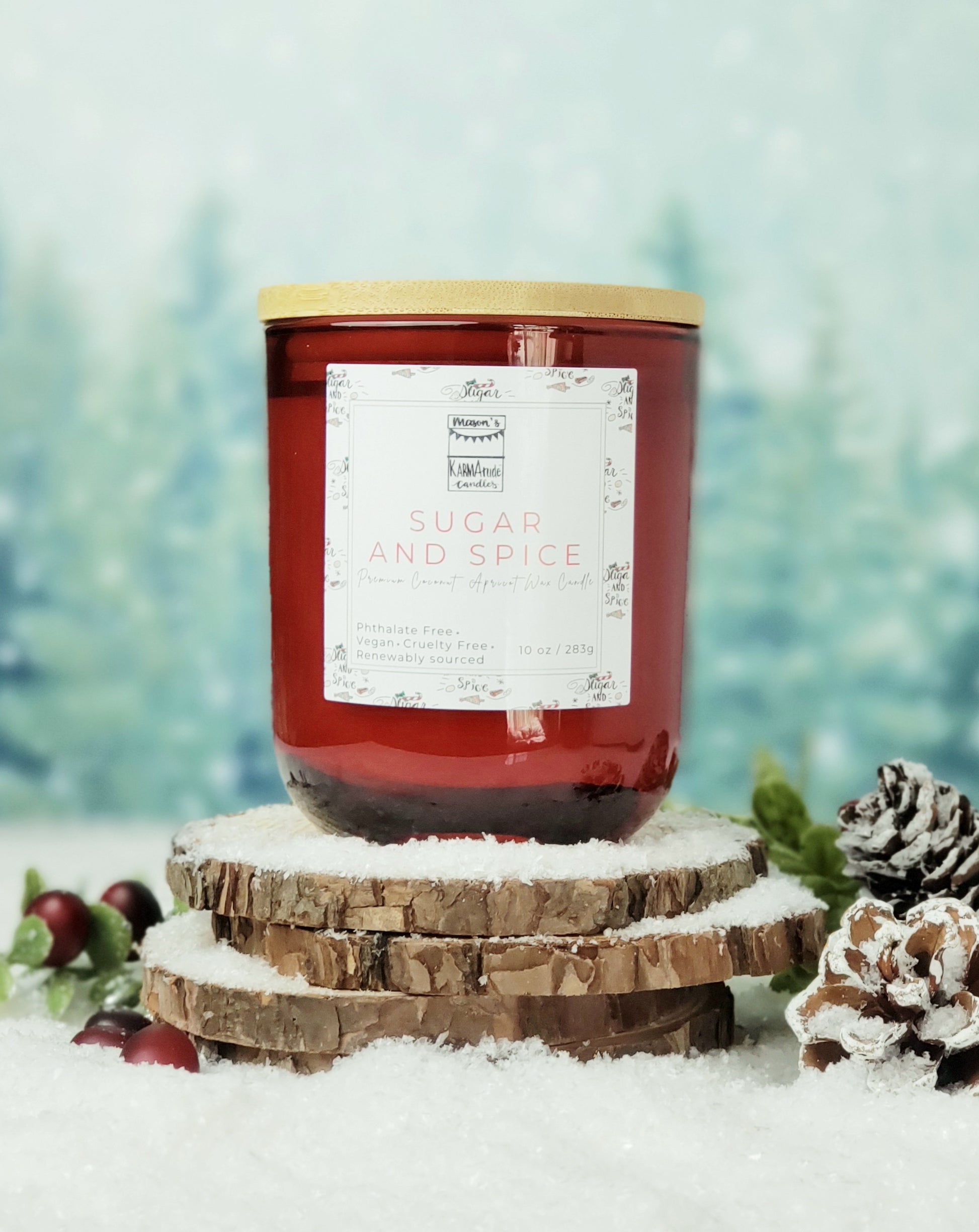 Picture of red glass candle with wood lid in Sugar and Spice scent on wood and snow platform.