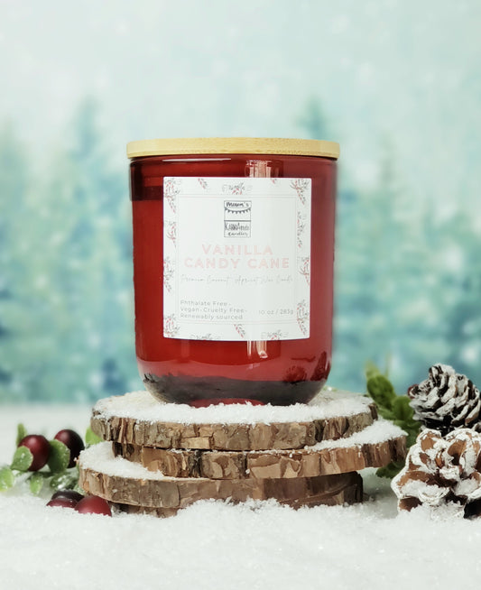 Picture of red glass candle with wood lid in Vanilla Candy Cane scent on wood and snow platform.
