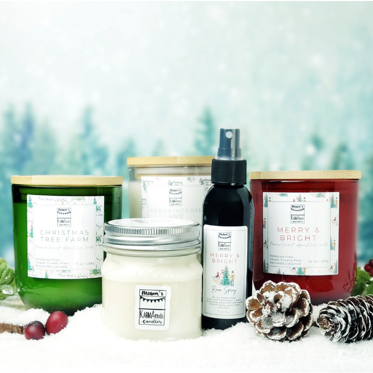 Assorted winter candles with clear glass, red glass, and green glass candles with wood lids. Also includes a glass jar candle with lid and room spray in a snowy setting and blurred forest background.